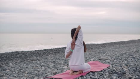 woman practicing yoga on a beach