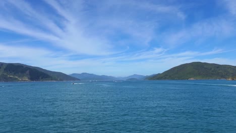 Boating-activity-on-beautiful-deep-blue-sea-bordered-by-land-in-summertime---Queen-Charlotte-Sound