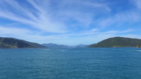 boating activity on beautiful deep blue sea bordered by land in summertime - queen charlotte sound