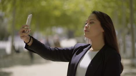 beautiful young woman taking selfie on street