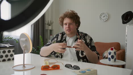 male fashion influencer comparing sunglasses as recording vlog at home