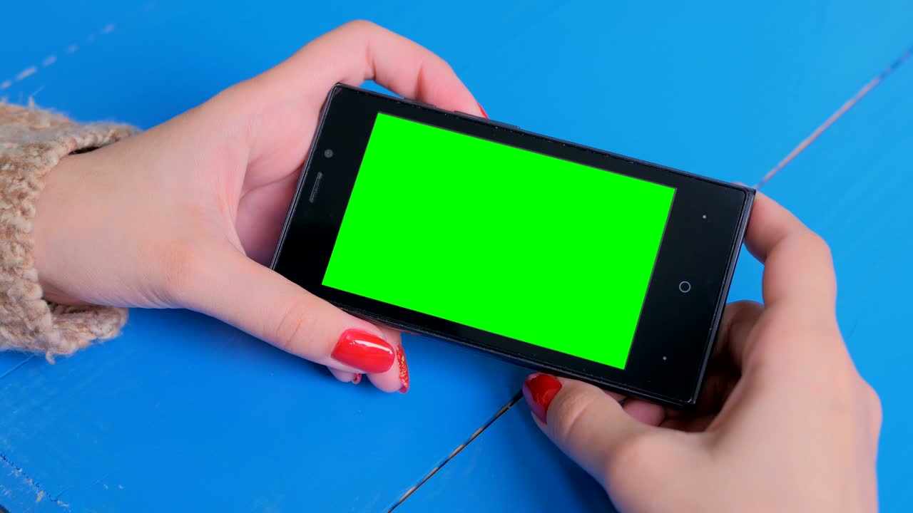 Woman looking at smartphone with green screen