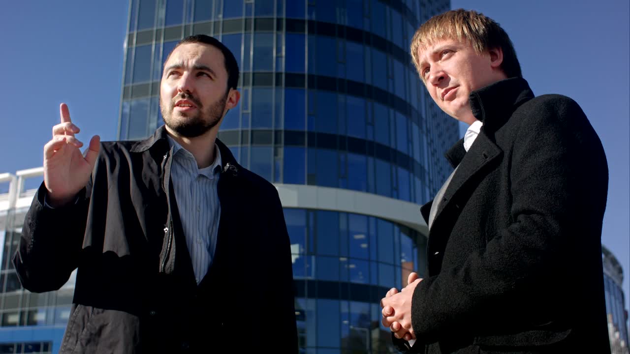 두 사업가 들 이 밖 에서 악수 를 하며 서로 인사 하고 있다