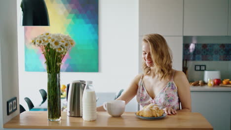 hermosa chica sentada en la mesa de la cocina y bebiendo café