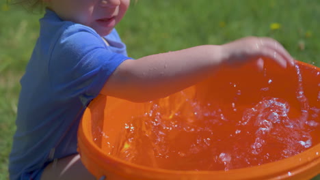 Slow-motion-of-toddler,-baby-splashing-water-and-getting-all-wet-on-a-hot-summer-day