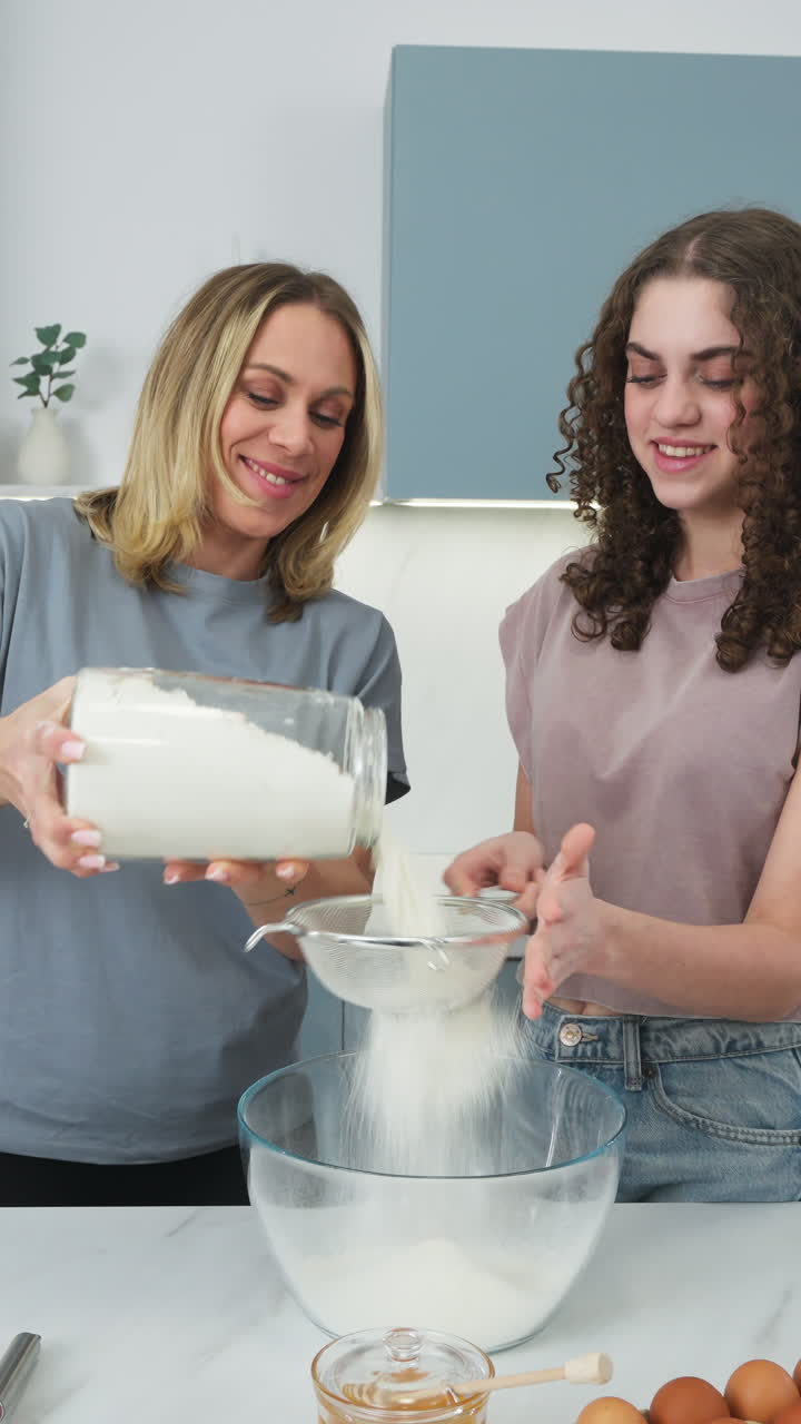 Tampilan Vertikal Dua Wanita Mengayak Tepung untuk Memasak Pancake. Pengambilan Gambar Jarak Dekat