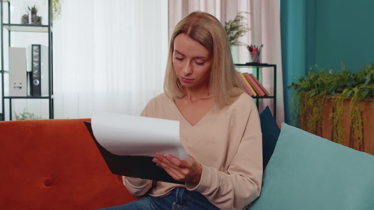 Girl reading paper documents, reviewing reports, calculate costs, incomes, expenses, working at home