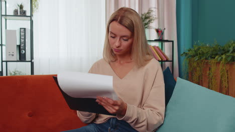 Niña-Leyendo-Documentos-En-Papel,-Revisando-Informes,-Calculando-Costos,-Ingresos,-Gastos,-Trabajando-En-Casa