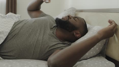 black man sleeping bed in morning. young male person stretching in bed slowly.