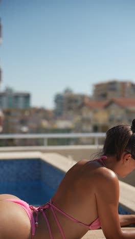 woman in pink bikini sunbathing by pool