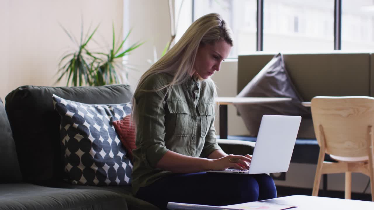 Caucasian businesswoman sitting and using her laptop in modern office