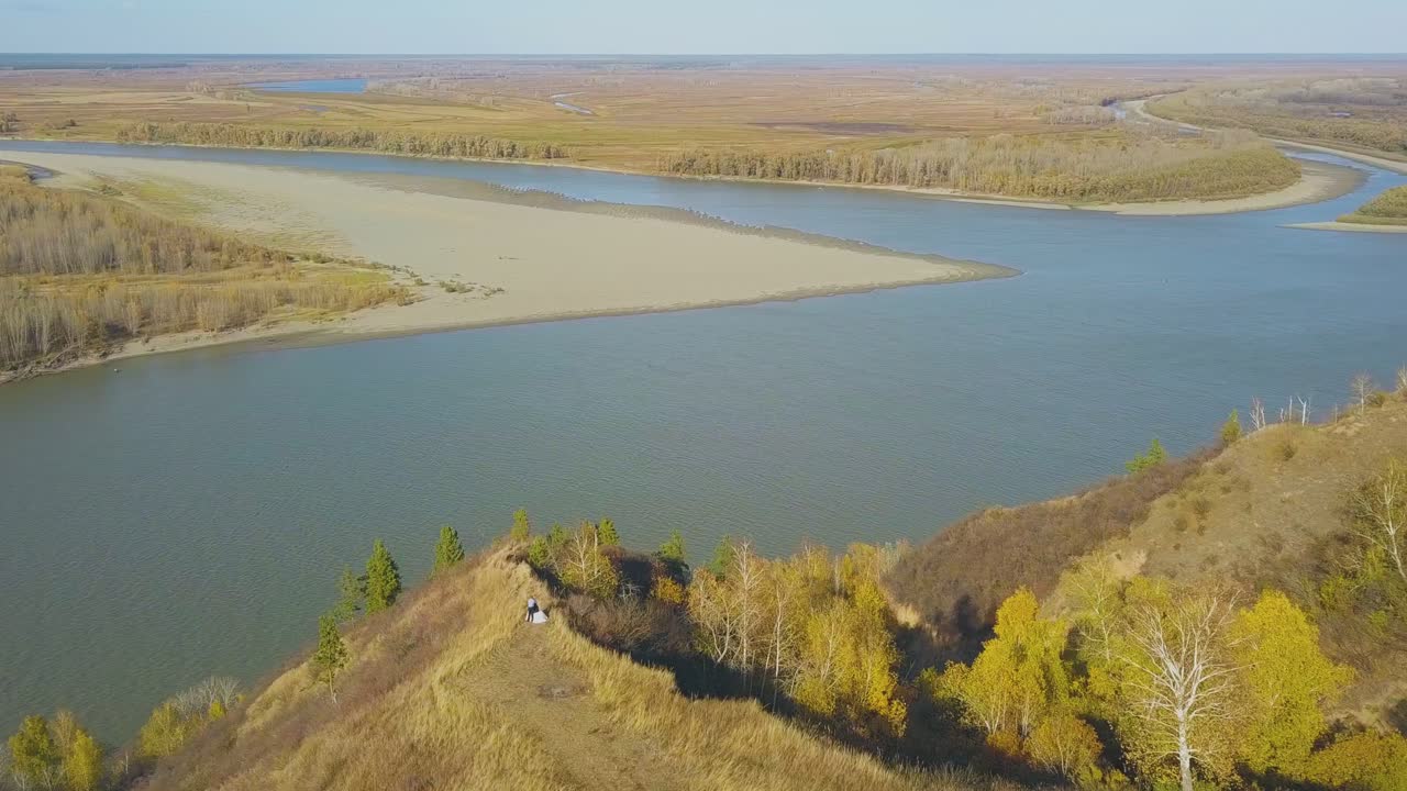 Nygifte par på stejl bakke nær flod, luftpanorama