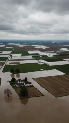 aerial view of a house and farmland submerged in floodwaters