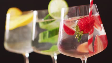 close up of drinks with fruit on black background