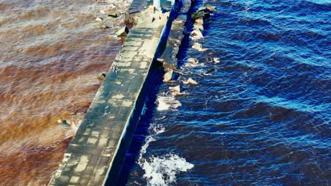 long concrete pier stretches into the deep blue waters of the baltic sea, where waves crash softly against the edge, highlighting coastal infrastructure