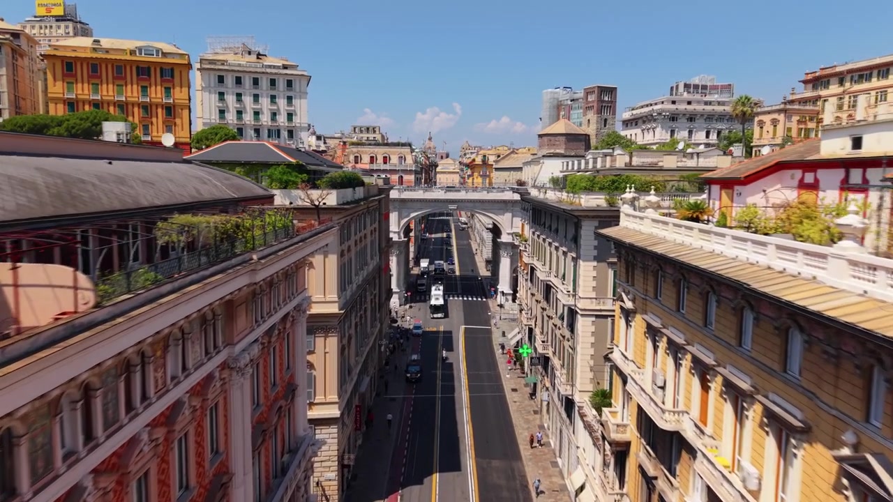 Drone voa entre edifícios históricos em direção a uma ponte no centro de Gênova, Itália