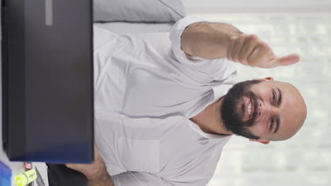 vertical video of home office worker man looking at camera clapping and getting excited.