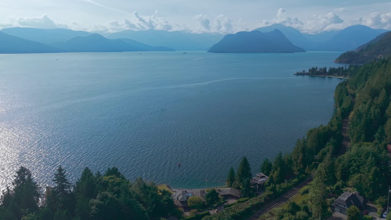 an aerial drone shot of a beautiful view of Bowen Island, Anvil Island and Tantalus and Serratus Mountains under the blue sky