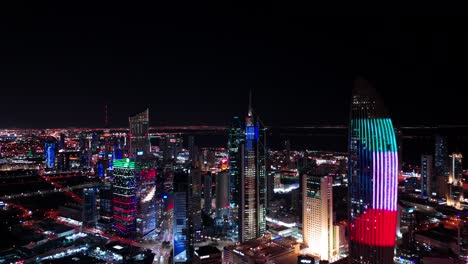 4k drone shot of kuwait city at night with towers lit in national colors. a vivid skyline, perfect for tourism, branding, and middle east urban themes.