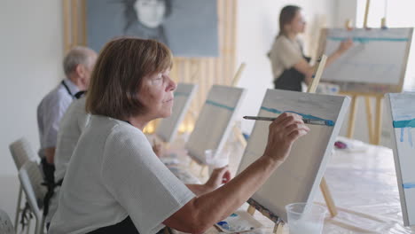 like senior friends attending together at a painting class. small group taking a variety of fun classes together. a group of elderly people attend a master class on drawing together spending time.