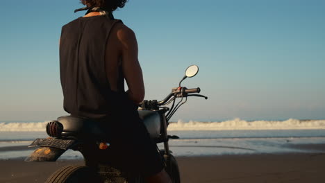 man on motorcycle at the beach at sunset