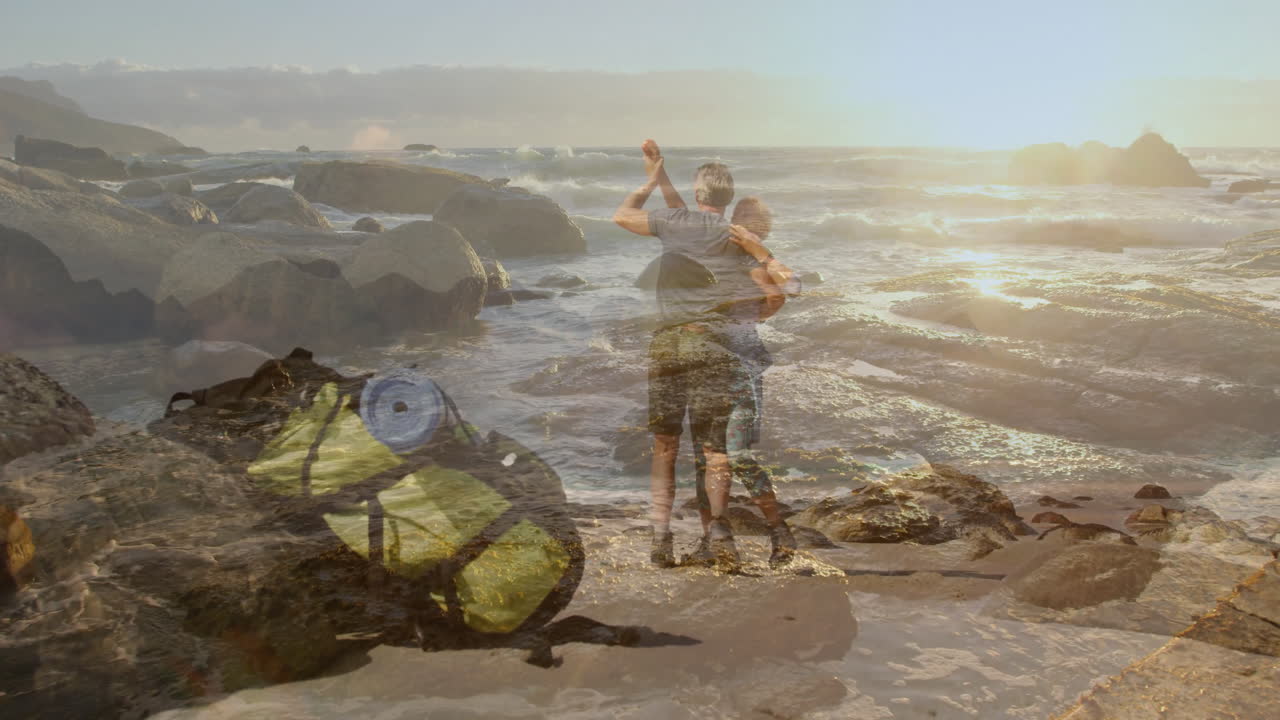 man and woman hugging on rocky beach near backpack and waves, featuring animated travel map overlay