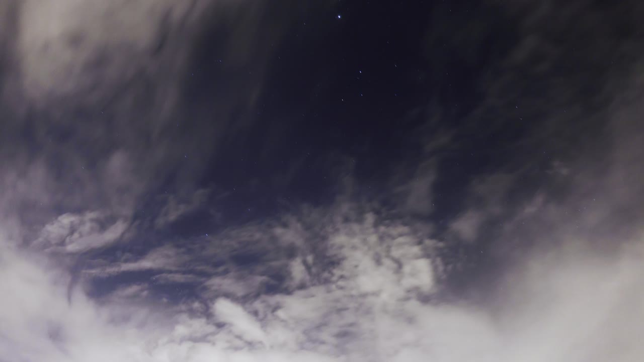 las nubes de tormenta se acumulan durante la noche mientras las estrellas se trazan en el cielo en el fondo