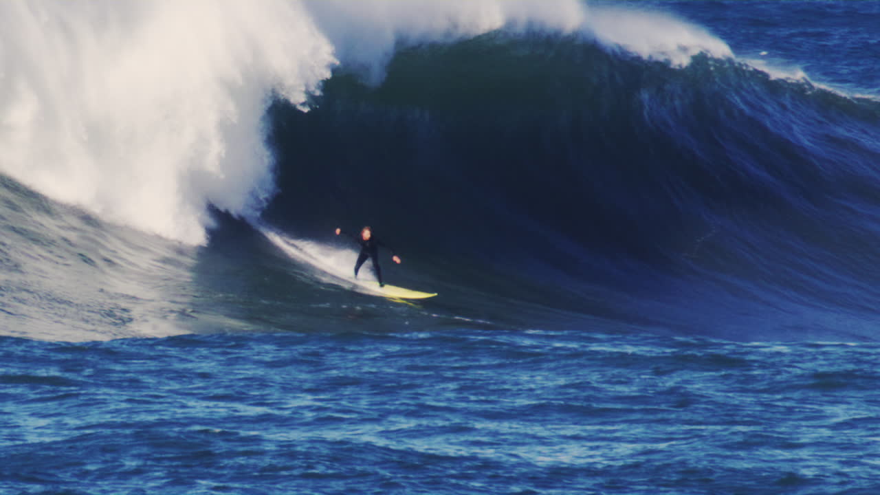 Slow motion view of surfer on longboard dropping in on monster huge ...