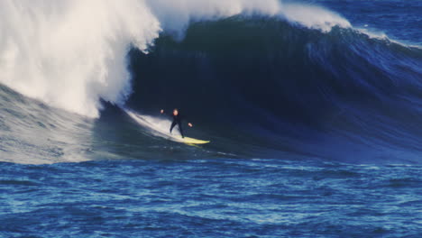 slow motion view of surfer on longboard dropping in on monster huge blue wave