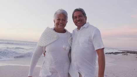 Happy-hispanic-just-married-senior-couple-walking-on-beach-at-sunset