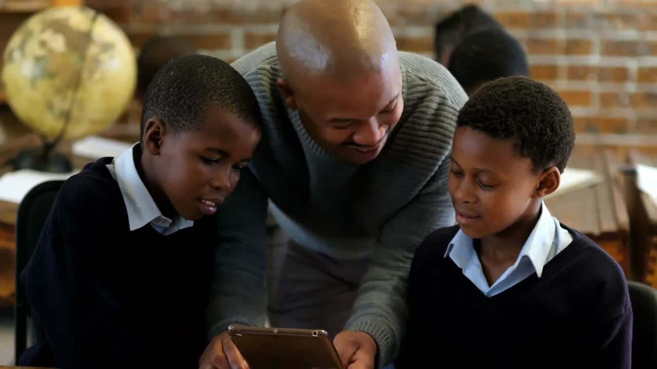Male teacher using digital tablet with students in classroom 4k