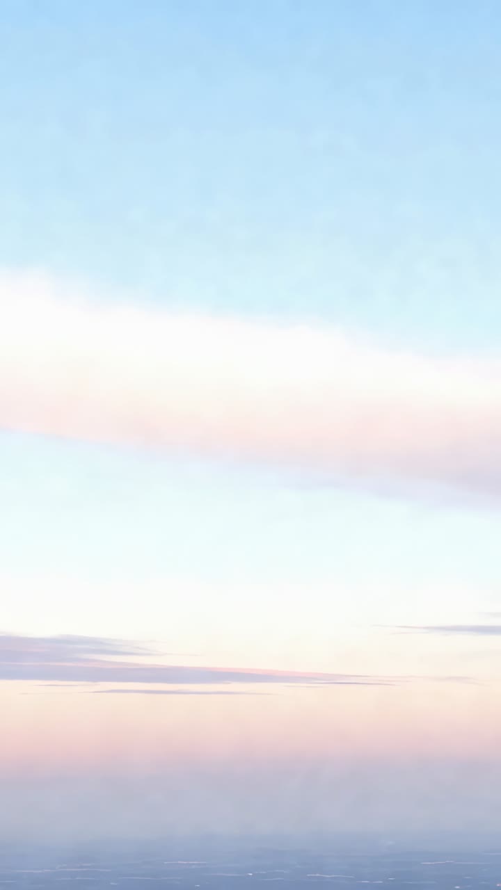Vertical video: Shifting pastel sky at dawn from subtle tilt, showing cloud band, dark line, haze