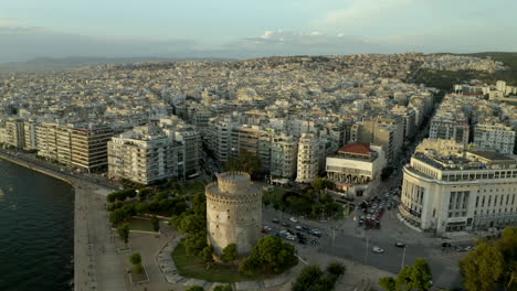 cinematic-Iconic,-historic-landmark-of-the-white-tower-of-Thessaloniki-drone,-aerial-shot-of-the-city-at-sunset-in-4k