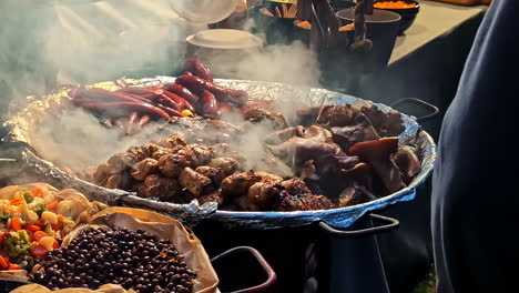 a bustling street food stall at the fisherman's day festival in engure, latvia, serves up hot, steaming grilled meat skewers and sausages from a giant pan
