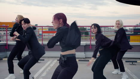 Five-girls-on-black-outfit-dancing-on-parking-lot