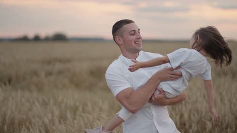 a father hugs and circles his beloved daughter at sunset. slow motion circling at sunset in the field of a girl