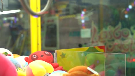 carnival lights sparkle through the glass of a claw game