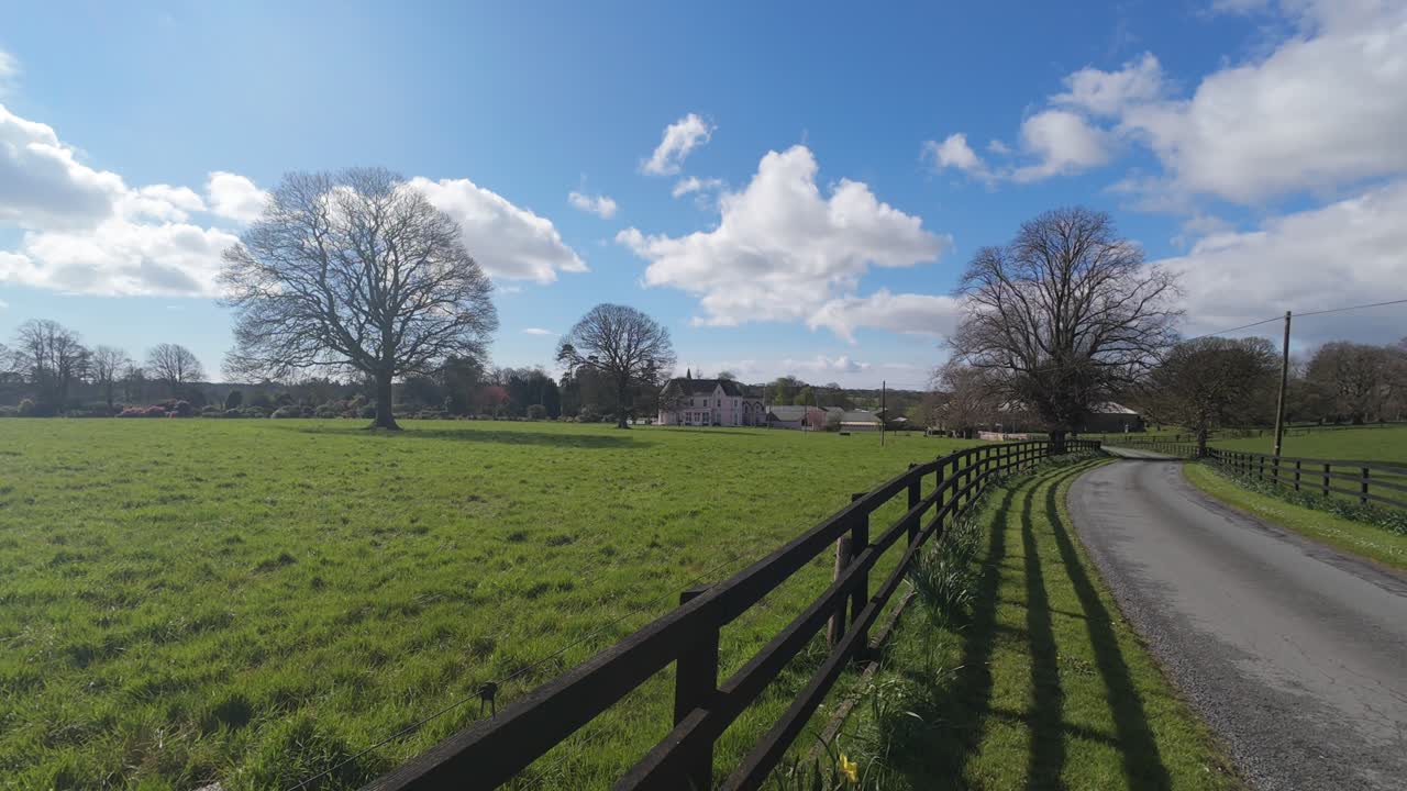 울타리와 주차로가 있는 아일랜드 농장, 밝은 봄 아침에 아름다운 나무와 난초