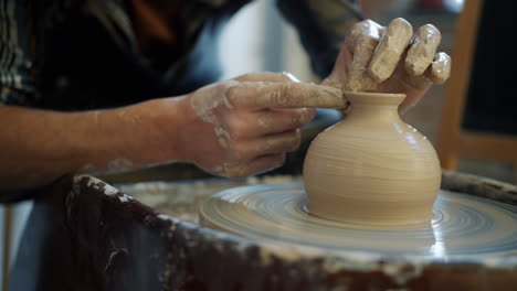 pottery artist shaping a vase on a pottery wheel