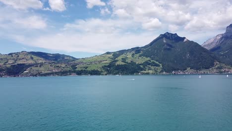 toma aérea panorámica del barco, el lago y las montañas suizas.