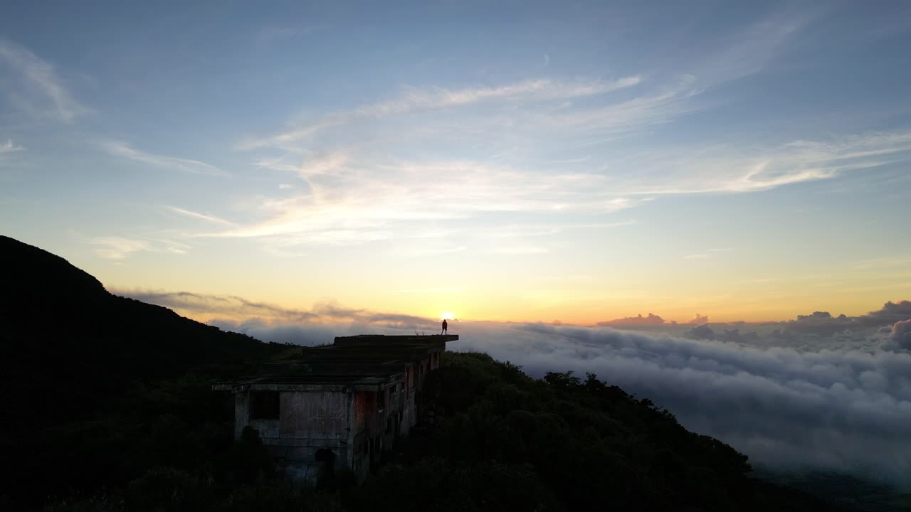 lone figure watching the sun rise above a sea of clouds on Isarog volcano in the Philippines