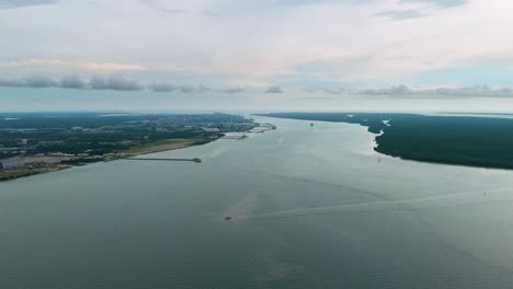 aerial view of westport in selangor, malaysia, stretching along the straits of malacca with calm waters, cargo terminals, distant vessels and coastal greenery under a cloudy sky. uhd.