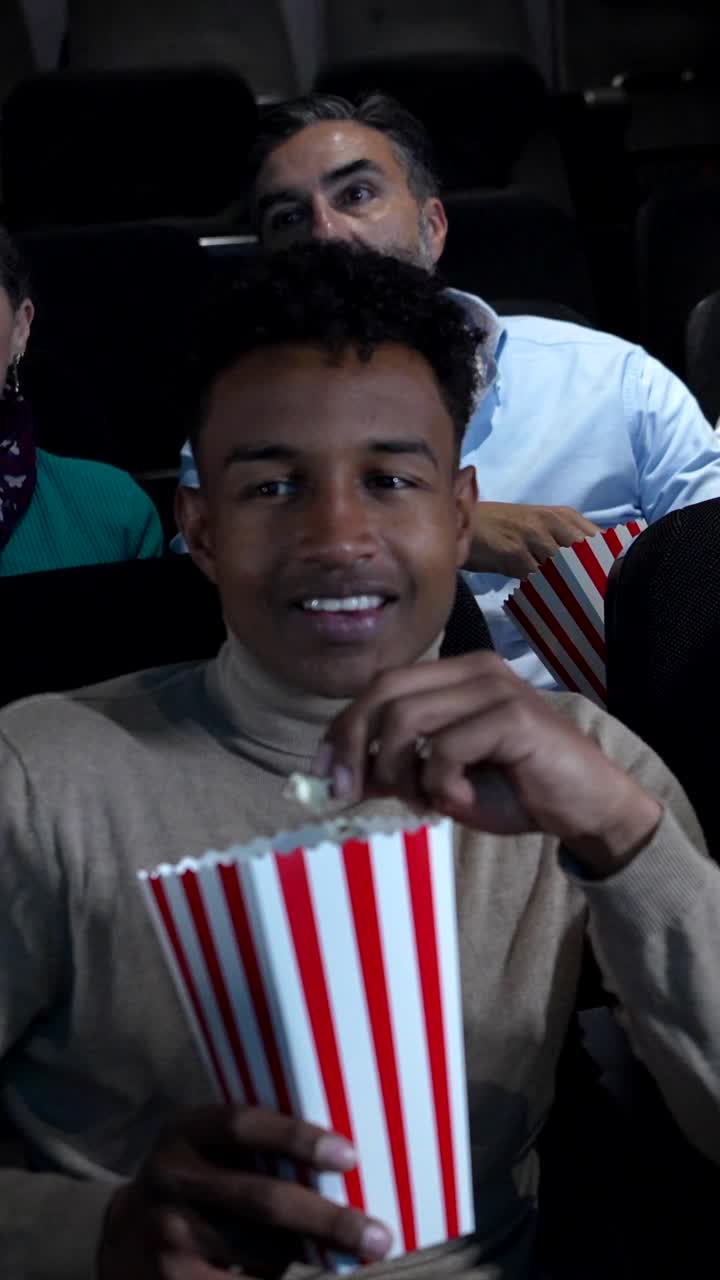People enjoying a movie with popcorn in a theater