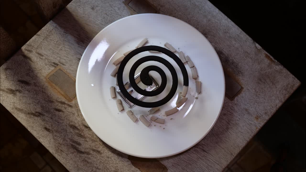 Mosquito coil repellent on a holder and plate burning time lapse top-down view
