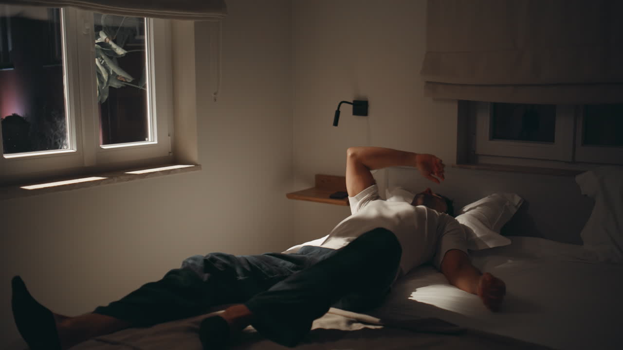 Restless man tossing bed trying fall asleep at night apartment. Exhausted guy