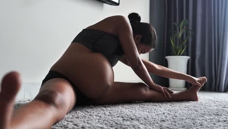 mujer embarazada haciendo ejercicio en casa, estirando las piernas y respirando.