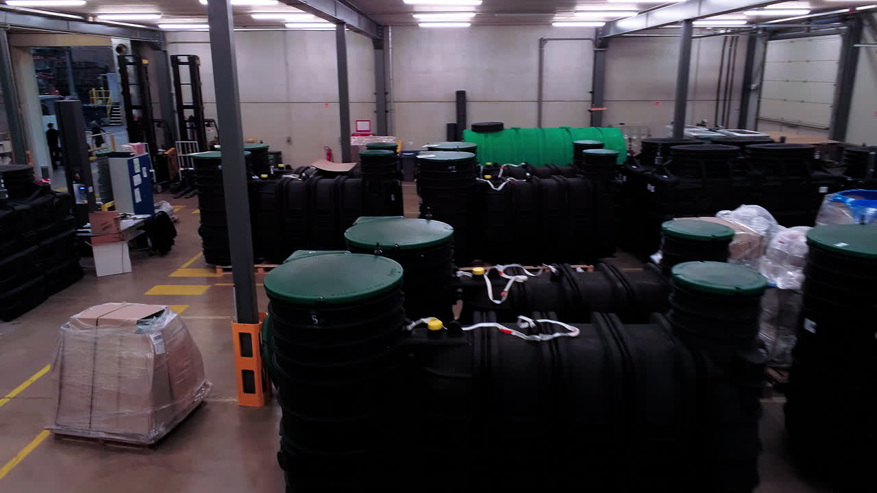 dentro de un centro logístico, toma aérea volando sobre muchos tanques de plástico listos para enviar fuera de la nave industrial