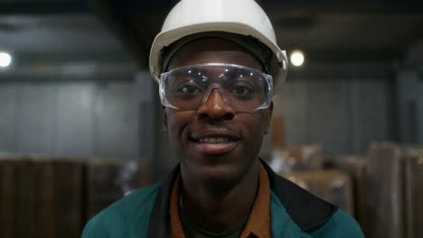 smiling factory worker in hard hat and safety glasses