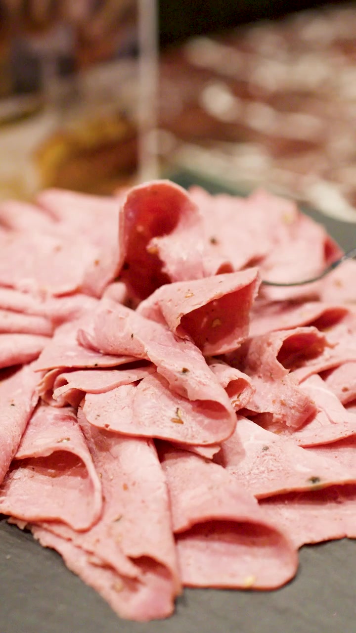 Primo piano di una forchetta che raccoglie roast beef a fette da un piatto di ardesia scura