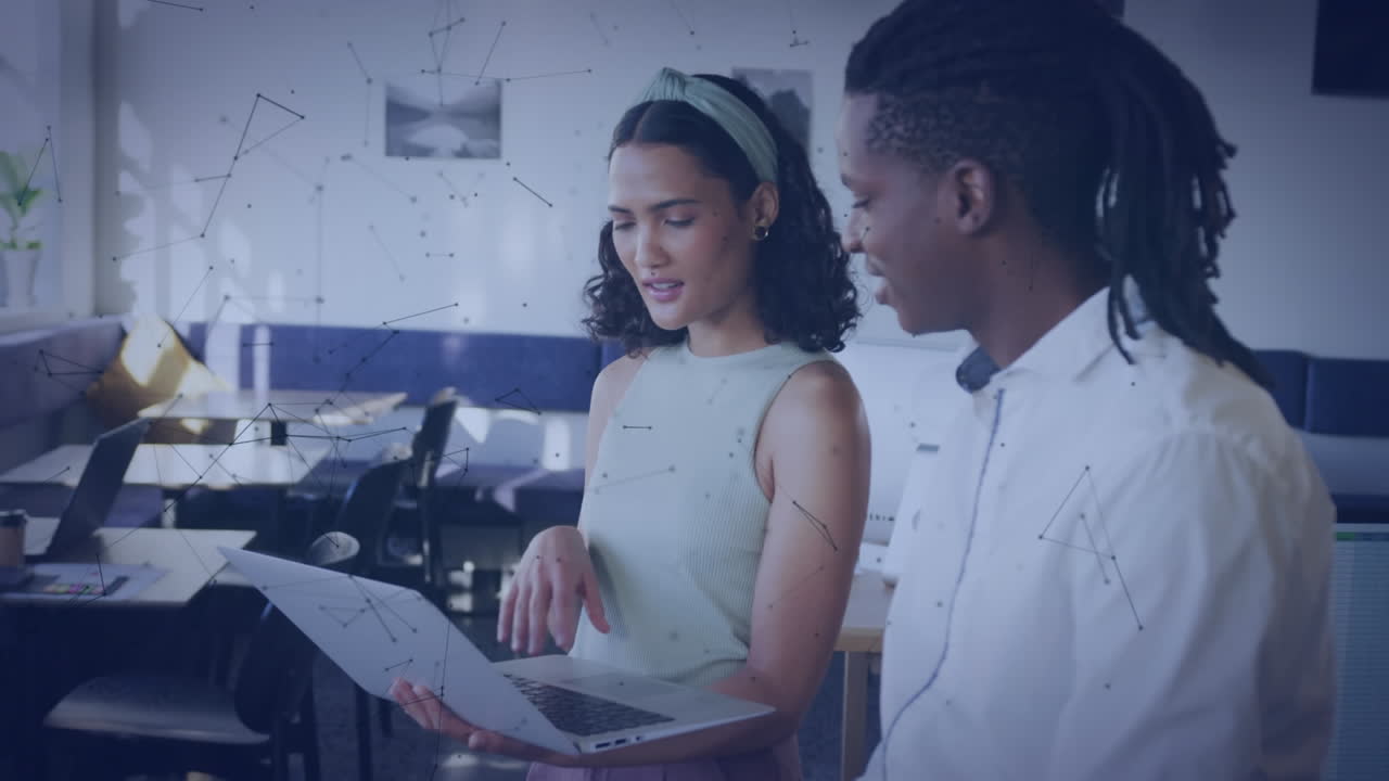 Animation of connected dots over diverse coworkers discussing report on laptop at office